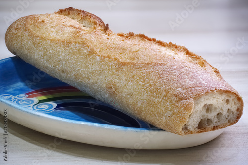 Freshly baked wholemeal sourdough bread baguette on rainbow decorative plate