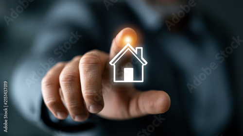 Businessman pointing at a glowing house icon to represent smart home integration and modern real estate solutions.