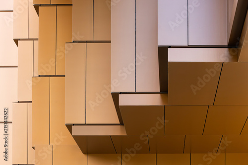 Abstract architectural detail of layered geometric panels in warm tones, showcasing modern design elements and textures in a contemporary urban setting