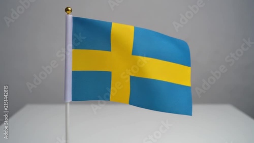 Small Sweden Flag Waving on White Table Desk Stand Isolated on Grey Background