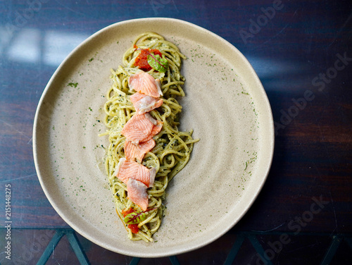 High-angle view of Japanese fusion seaweed carbonara pasta topped with salmon slices and tobiko fish roe