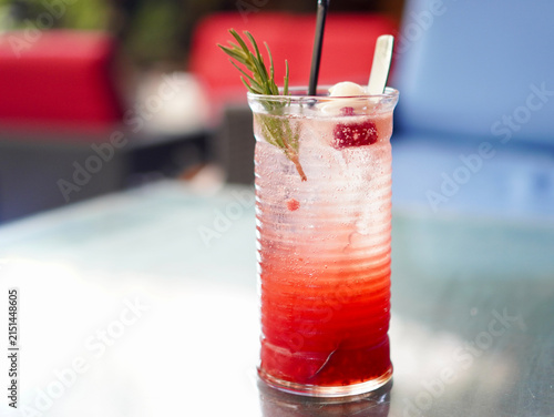 Sparkling lychee raspberry iced tea mocktail topped with a fresh lychee and fragrant rosemary sprig