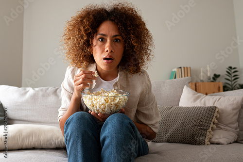 Young woman watching horror movie reaction at home