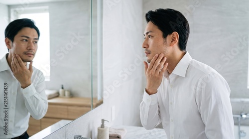 鏡の前で肌の状態を確認する男性