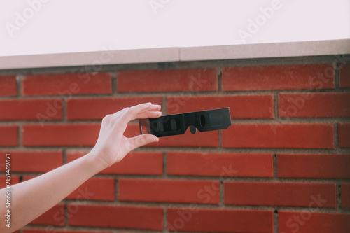 Una mano sujetando unas gafas para la observación segura de un eclipse solar. Gafas para el eclipse de agosto de 2026