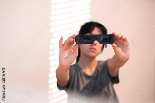 Una mujer sujeta unas gafas negras para ver un eclipse. Protección solar para la observación segura de un eclipse total. Accesorio para observar el eclipse de agosto de 2026 en España