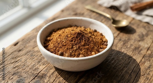 Ground Pumpkin Pie Spice in White Ceramic Bowl on Rustic Wood, Autumn Baking Ingredient Concept