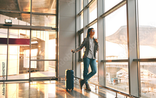Foto A young woman, wearing a grey blazer and jeans, stands at ease beside a large fl