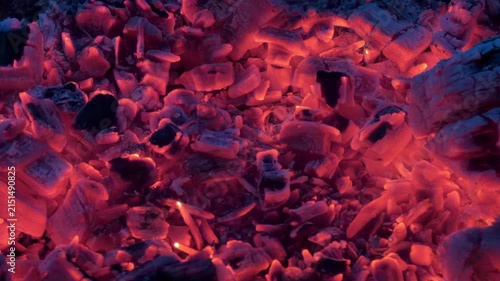 Panning over red hot coals glowing and flickering in a wood fire in 4K footage