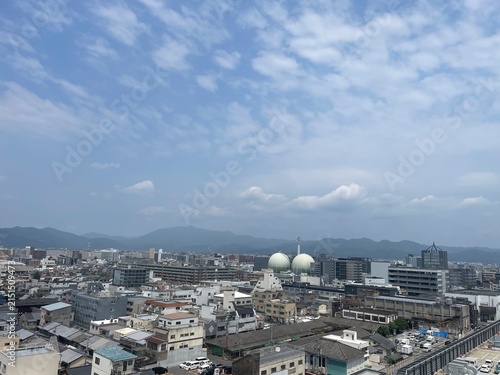 Bild auf Leinwand 青空とうろこ雲の下に広がる都市の景観とガスタンク
