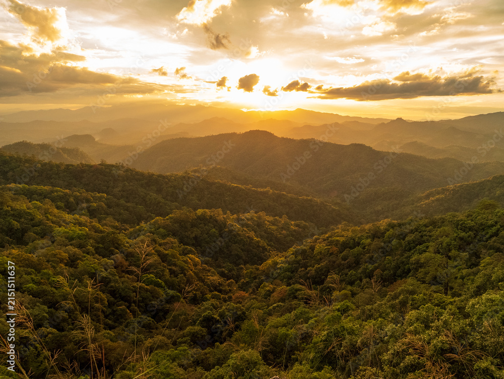 Obraz premium Dramatic sunset over mountain landscape. Dawn sky gold dusk time cloudscape with sunlight. Blue golden sky sunrise dramatic beautiful landscape mountain. Beautiful landscape foggy hills twilight time