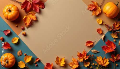 Autumn leaves and small pumpkins arranged on colorful background, creating warm and festive fall atmosphere