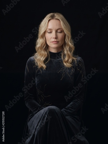 Contemplative Blonde Woman Wearing Elegant Black Evening Gown