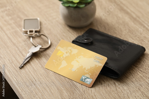 Photography Golden credit card on a wooden table with a black wallet and house keys, financi