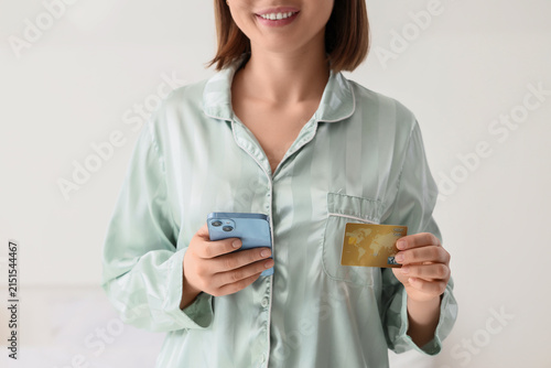 Woman with credit card and mobile phone in bedroom