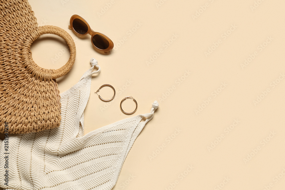Obraz premium Female summer dress with beach bag, sunglasses and earrings on beige background