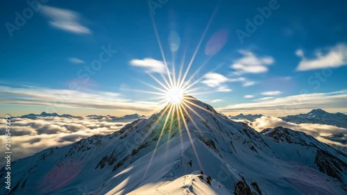 Snow covered mountain peak above clouds at sunrise