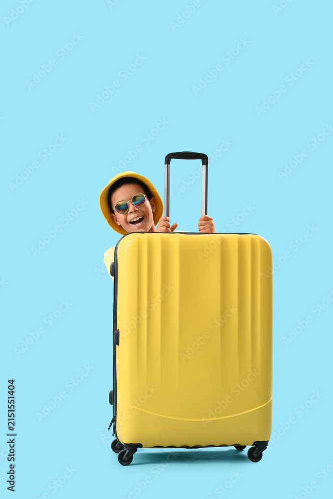 © Pixel-Shot - Happy African-American boy hiding behind suitcase on blue background © Pixel-Shot - Happy African-American boy hiding behind suitcase on blue background