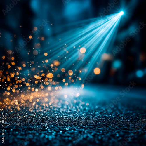 Blue spotlight shining down on shimmering glittering surface with spotlight, darkness