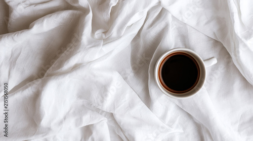 White Ceramic Cup of Black Coffee on Rumpled White Bed Sheets Morning Lifestyle Concept Calm luxury visual identity.