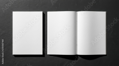 Blank white magazine mockup with closed cover and open spread featuring two empty pages on a textured black slate background, top view flat lay with sharp shadows for graphic design display.