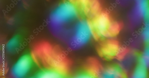 Bokeh glitter flare. Blur light. Pink green blue color radiant illuminated rainbow flash on abstract optical art black luminous background.