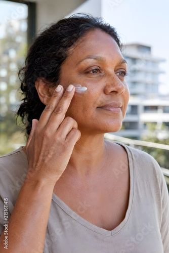 Aboriginal Australian Woman Applying Mineral Sunscreen on Cheek Outdoors on Balcony with Smile