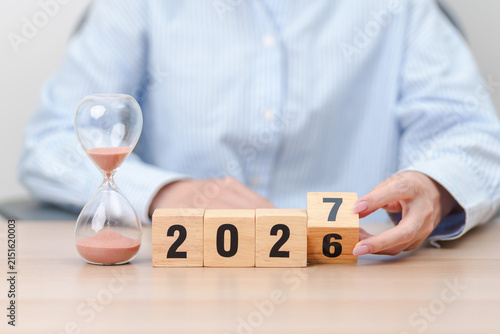 2026 end year to Happy New Year 2027 with hourglass on table. Resolution, time, plan, goal, motivation, reboot, countdown and New Year holiday concepts