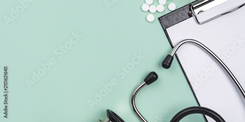 Stethoscope with Medical Clipboard and Pills on Mint Green Background