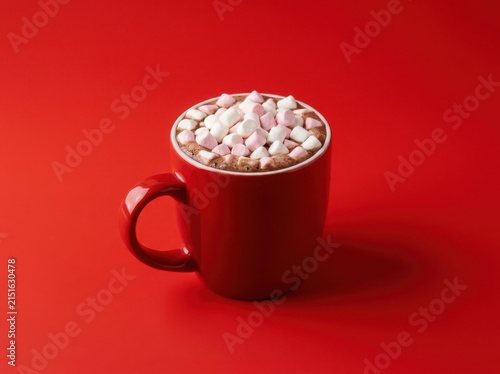 A bright red mug filled with hot cocoa and white pink marshmallows