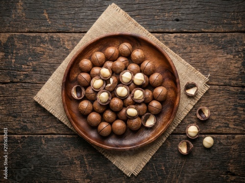 A wooden bowl filled with fresh macadamia nuts on rustic wooden table