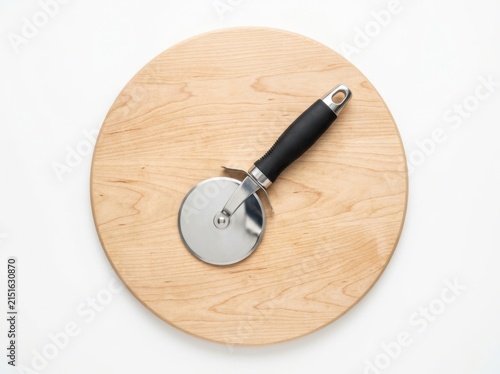 A Stainless Steel Pizza Cutter Resting On A Round Wooden Cutting Board