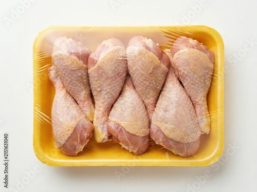 A top down view of fresh raw chicken drumsticks in yellow packaging