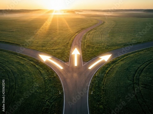 A three way road junction with glowing arrows pointing towards the sunrise