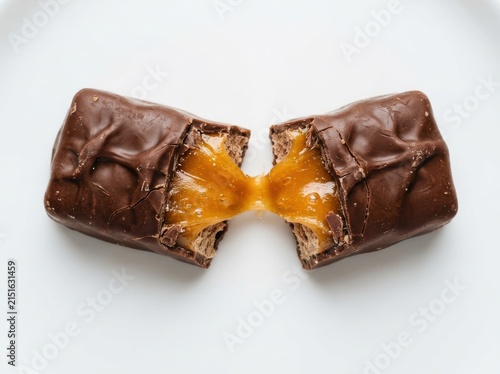 A delicious chocolate candy bar broken in half revealing gooey golden caramel