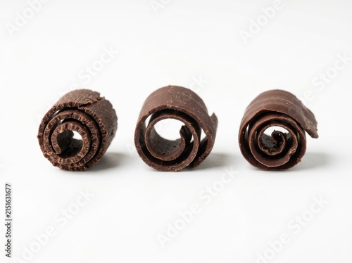 Three delicate dark chocolate curls isolated against a clean solid white background