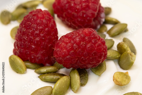 Creamy Greek Yogurt Topped with Pepitas and Three Fresh red raspberries in a Clear Glass Bowl