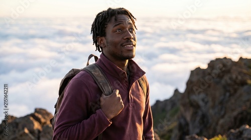Young male hiker looks upward with awed gratitude above a luminous sea of clouds, gripping his backpack strap as sunrise reveals the emotional reward of reaching the mountaintop without companions