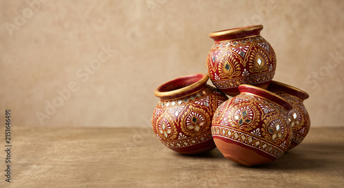 Decorated Indian terracotta clay pots with traditional red and gold patterns arranged on a rustic surface for Diwali and festive decor