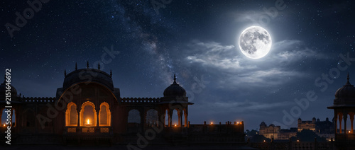 Illuminated Indian palace under a full moon and starry night sky with glowing diyas evoking heritage architecture and a festive atmosphere