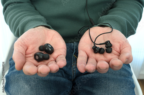 Foto Persona comparando auriculares inalámbricos y auriculares con cable