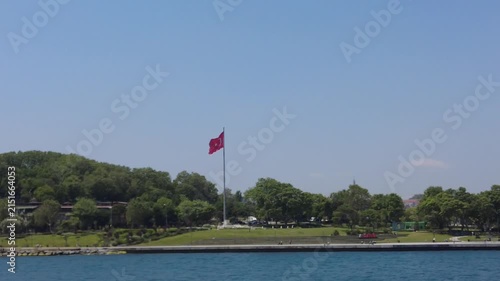 トルコ・イスタンブールの海岸に掲げられた大きなトルコ国旗をフェリーから望む風景｜エミノニュから出港後の眺め
