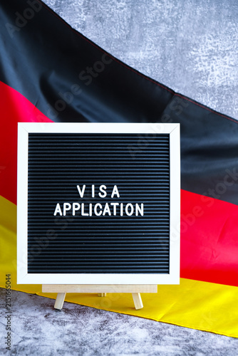 Letter board text VISA APPLICATION National symbol of Germany. German wave silky flag background. Concept of temporary work permit employment migration
