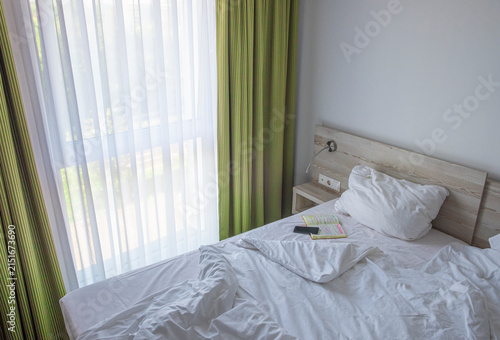 A smart phone and a note book on a neatly made hotel bed, symbolizing a peaceful morning routine.