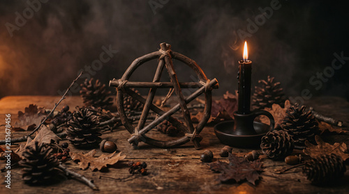 Occult harvest altar with wooden pentagram and black candle.