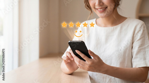 Smiling woman using smartphone with five star rating and smiley face. Customer satisfaction concept