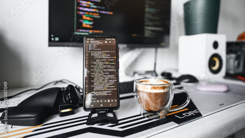 Stylish technology workspace combines programming monitor, audio speakers, smartphone, coffee in minimalist interior. Inspiring environment for developers, creators, remote professionals. Vibe coding