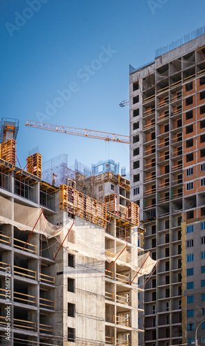 Tall apartment building under active construction with crane illustrates expanding city infrastructure. Clean composition highlights modern engineering, investment opportunities and residential growth