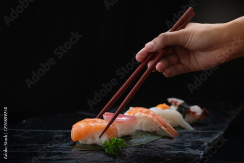 Close-up image of a hand holding chopsticks and picking up sushi sashimi. Traditional Japanese culinary concept.