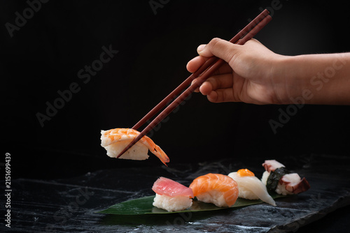 Close-up image of a hand holding chopsticks and picking up sushi sashimi. Traditional Japanese culinary concept.
